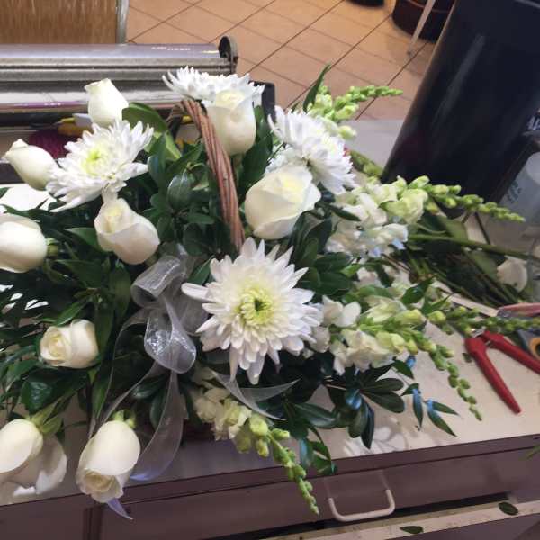 White roses and daisies arranged with greenery in a basket