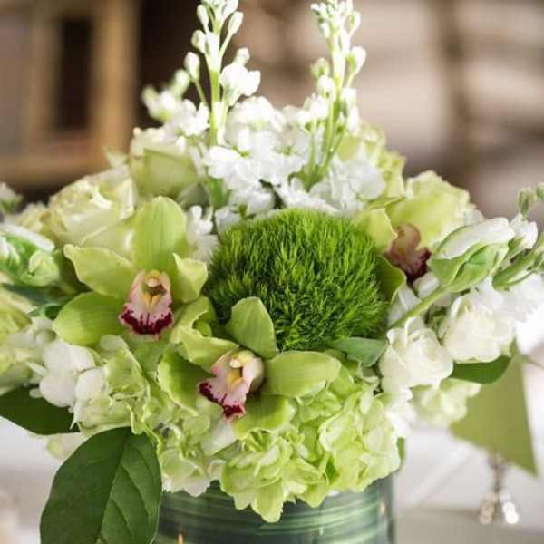 Green and white floral arrangement in a glass vase