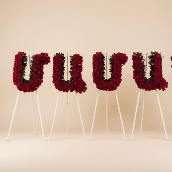 Four red floral letter arrangements on white easels