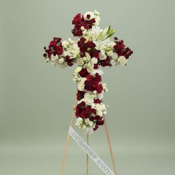 Cross-shaped floral tribute of red and white roses on a stand
