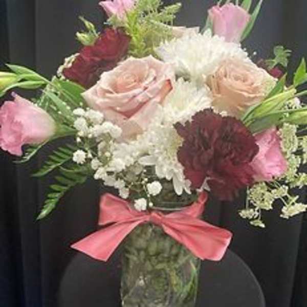 Mixed pink and white bouquet in a glass vase with a pink ribbon