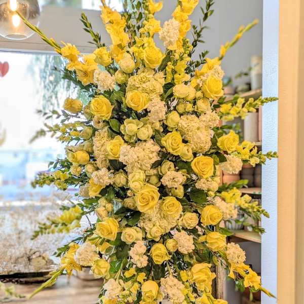 Tall yellow and white floral standing arrangement on an easel