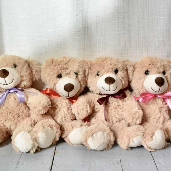 Four plush teddy bears with ribbon bows sitting in a row