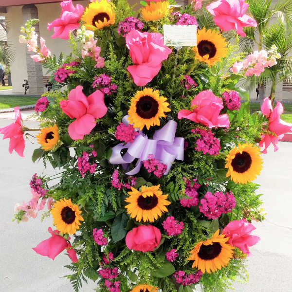 Standing floral spray with pink flowers and sunflowers on an easel