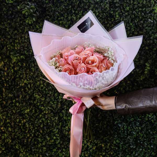 Pink rose bouquet wrapped in pale pink paper with a ribbon