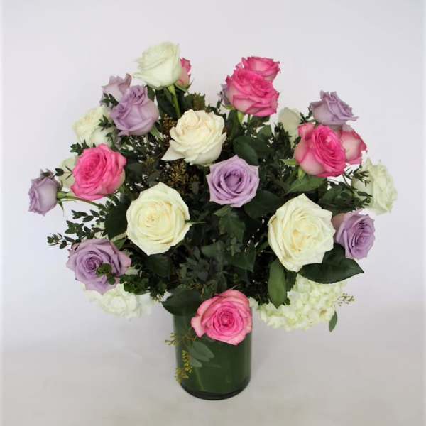 Bouquet of pink, lavender, and white roses in a green glass vase