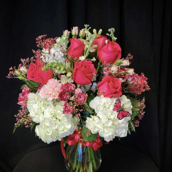 Pink roses and white hydrangeas in a glass vase with a ribbon