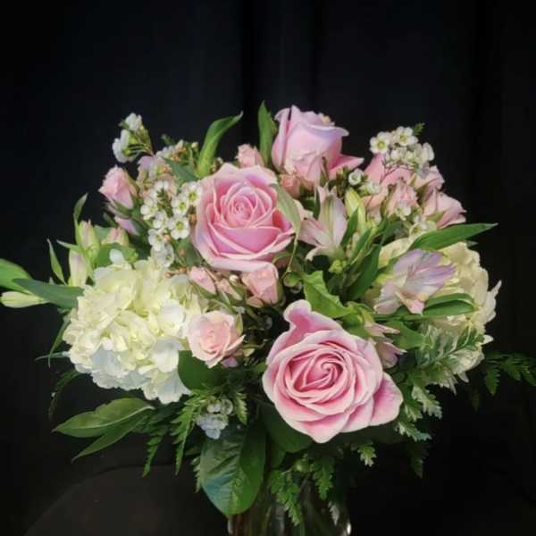 Pink roses and white hydrangeas arranged in a clear glass vase