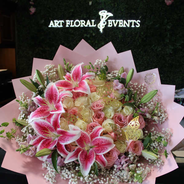 Pink and white bouquet with lilies and roses wrapped in pink paper