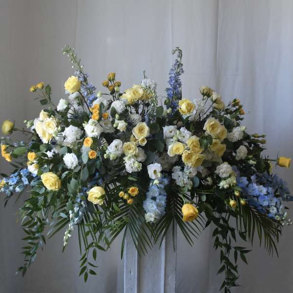Large floral spray with yellow roses, white blooms, and blue flowers
