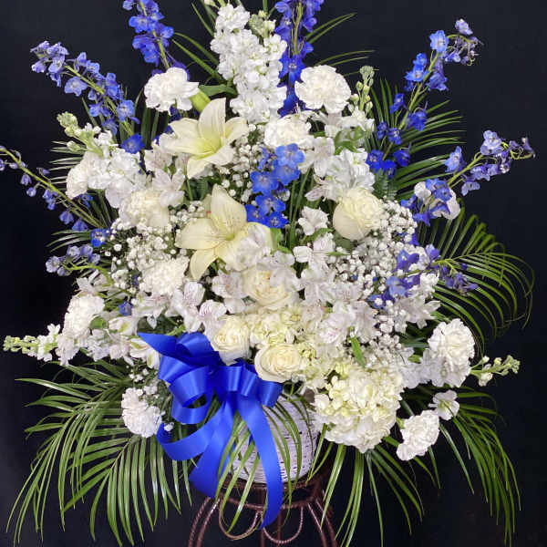 White and blue floral arrangement in a basket with a blue ribbon