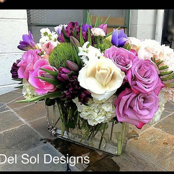 Mixed bouquet of pink, purple, and white flowers in a glass vase