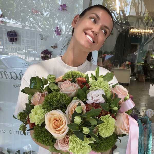 Woman holding a pink box of pastel roses and green carnations