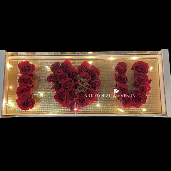 Red roses arranged to spell "I U" in a lit display box