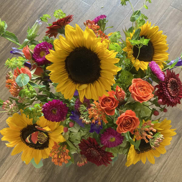 Mixed bouquet with sunflowers, orange roses, and bright accent flowers