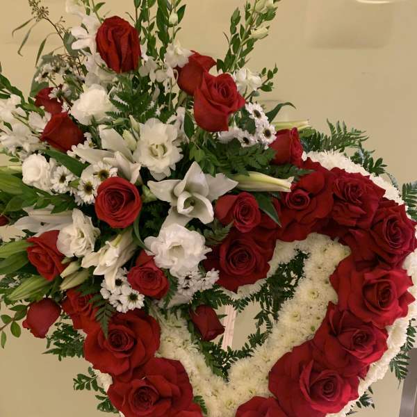 Heart-shaped red and white floral standing arrangement on an easel