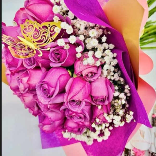 Bouquet of pink roses with white baby's breath wrapped in bright purple paper