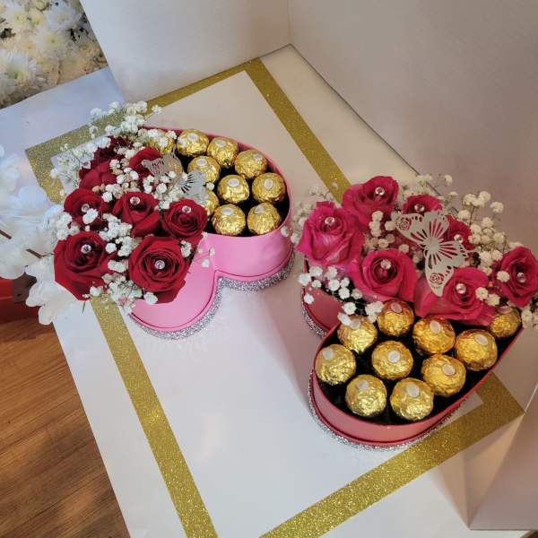 Heart-shaped boxes with red roses and gold-wrapped chocolates