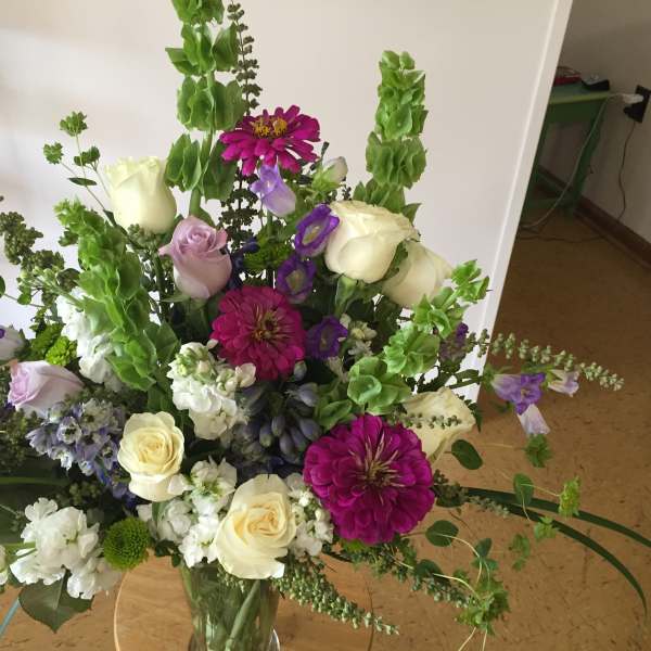 Tall mixed bouquet in a glass vase with white roses and purple flowers