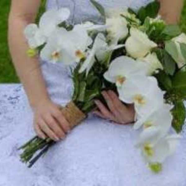 Bride holding a white orchid bouquet with greenery