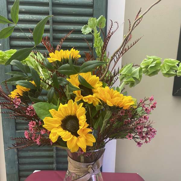 Sunflower bouquet in a clear glass vase with pink filler flowers