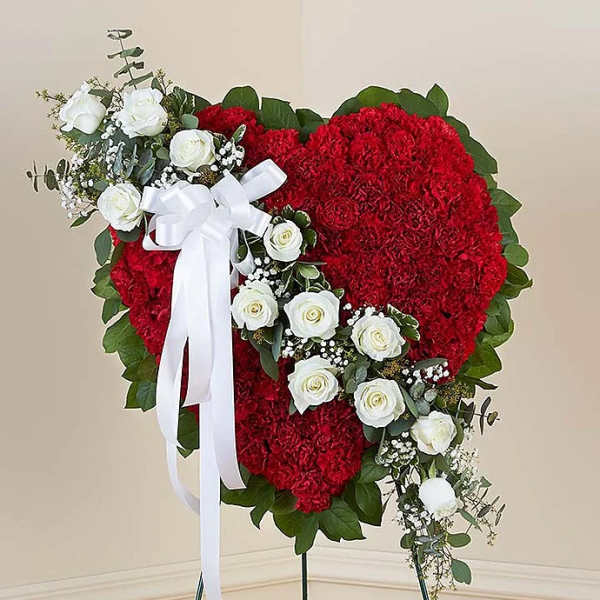 Heart-shaped red floral wreath with white roses and a white ribbon