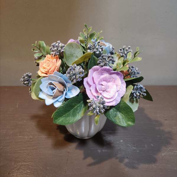 Small pastel floral arrangement in a silver vase with blue and lavender blooms