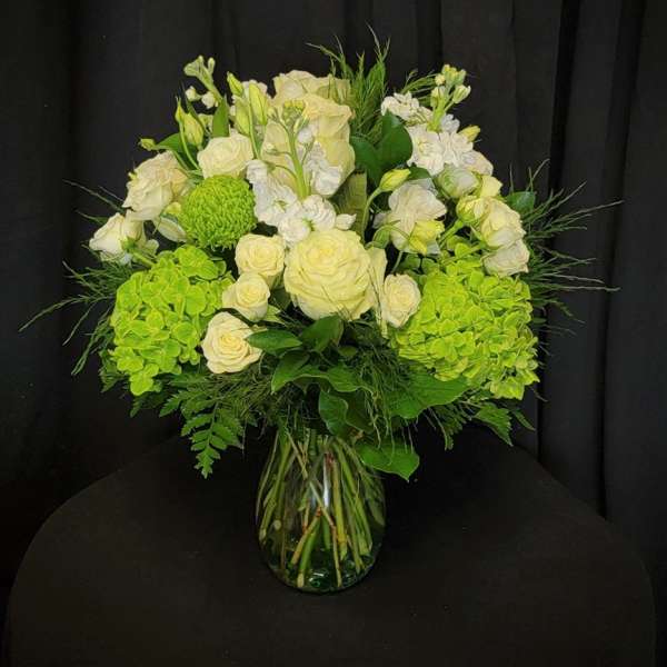 White roses and green hydrangeas in a glass vase
