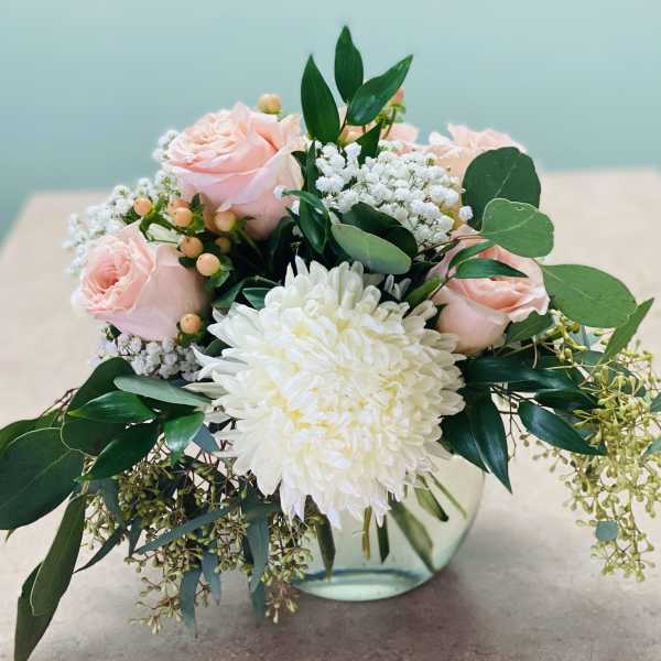 Pink roses and a white chrysanthemum in a glass vase