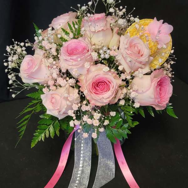 Pink roses with baby's breath and ribbon accents in a bouquet