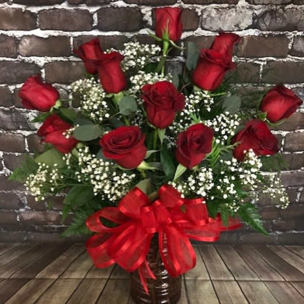 Red roses in a vase with baby's breath and a red ribbon bow
