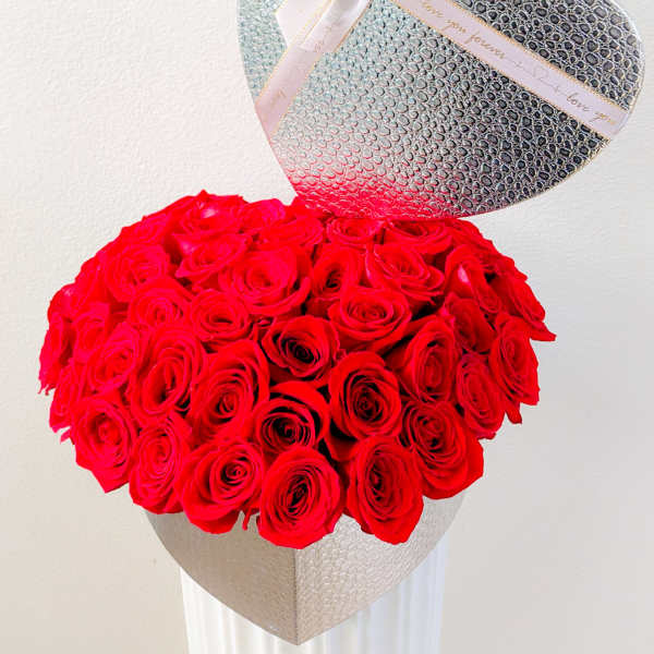 Heart-shaped box of red roses with a silver heart topper and ribbon