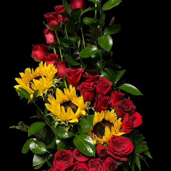 Tall arrangement of red roses and yellow sunflowers in a vase