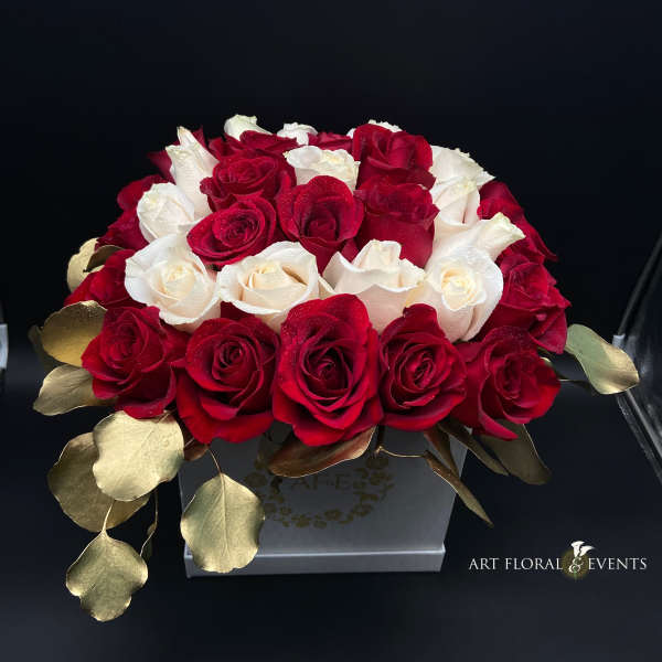 Red and white roses arranged in a square box with gold leaves