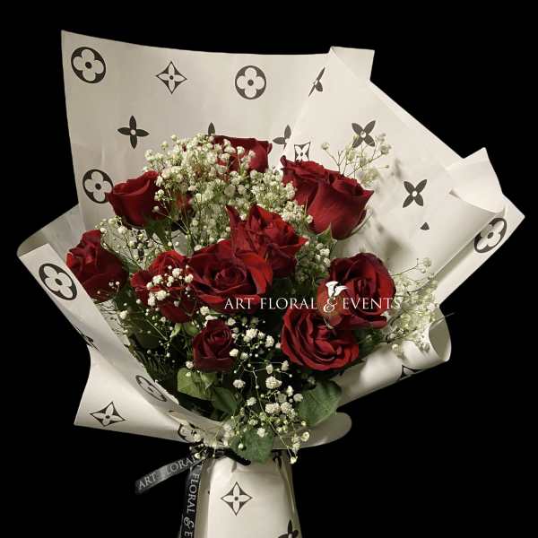 Bouquet of red roses with baby's breath in patterned white wrap