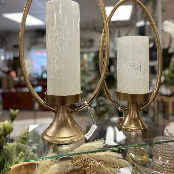 Two gold candle holders with white pillar candles
