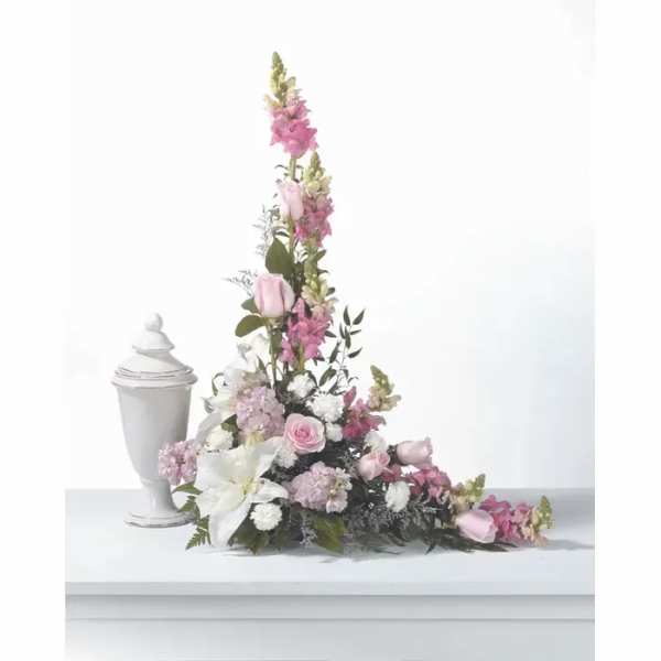 Tall pink and white floral arrangement beside a white urn