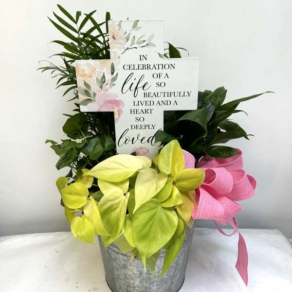 Potted plant arrangement with a memorial cross sign and pink ribbon