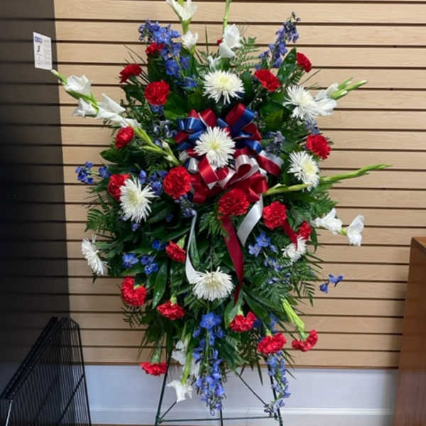 Standing floral spray with red, white, and blue flowers on a metal easel
