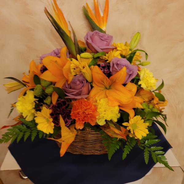 Basket arrangement of orange lilies, purple roses, and yellow daisies