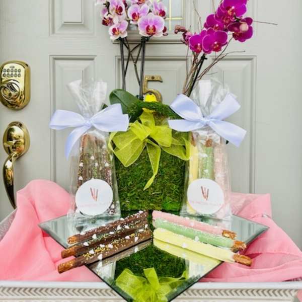 Orchid arrangement with gift bags and chocolate-covered pretzel rods