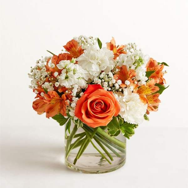 Orange and white flower arrangement in a clear glass vase