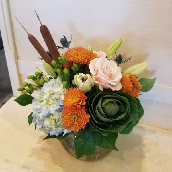 Mixed bouquet in a glass vase with orange and pale pink blooms
