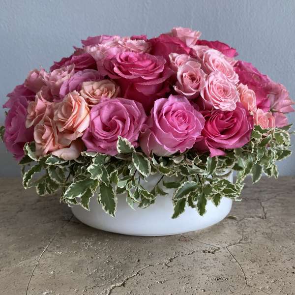 Pink and peach roses arranged in a white bowl vase