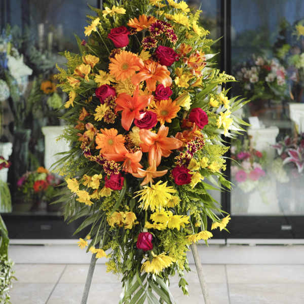 Tall standing floral spray with orange, yellow, and red blooms