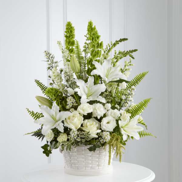 White lilies and roses arranged in a white basket