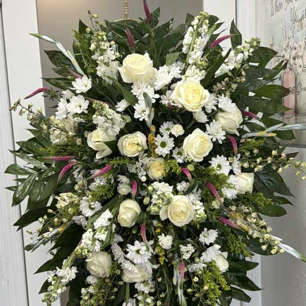 Large white floral standing spray with roses and daisies on an easel