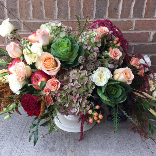Mixed bouquet with roses, hydrangeas, and apples in a white vase