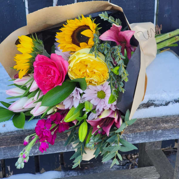 Bouquet of sunflowers, roses, lilies, and daisies wrapped in paper