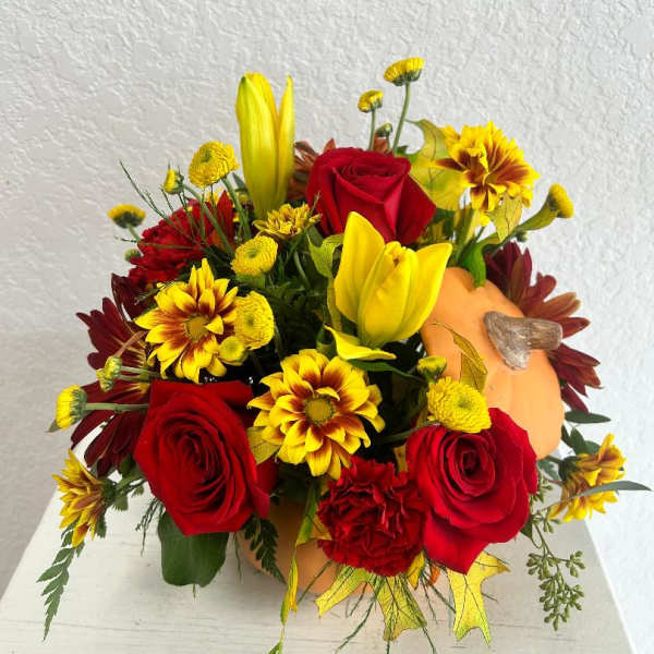 Bouquet of red roses, yellow lilies, and daisies with a small pumpkin